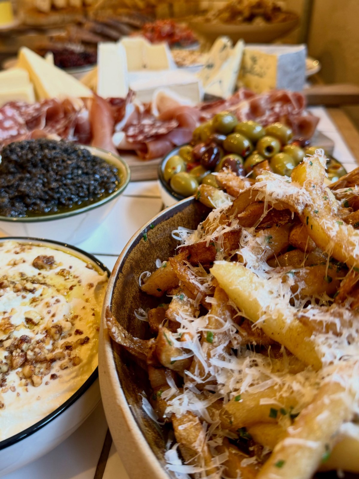 Elder grazing table with small plates, cheese, charcuterie and olives